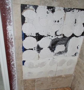 The builder’s solution to the voids under the wall tile was to pour a slurry behind the installed tiles to fill in the spaces.